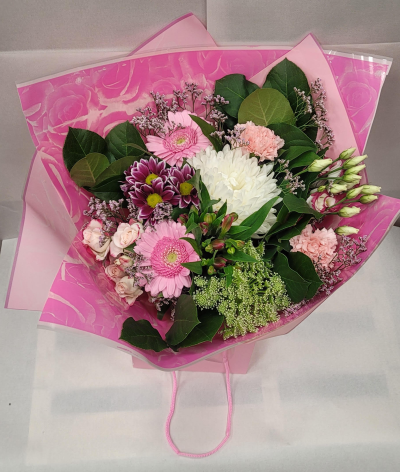 Blossom Pink Delight - A charming bouquet featuring a soft and cheerful mix of pink, white, and purple blooms. Light pink gerbera daisies, delicate roses, and fluffy carnations pair beautifully with a large white chrysanthemum at the center. Accents of purple chrysanthemums, dainty filler flowers, and lush green foliage add depth and texture. Wrapped in vibrant pink floral paper and presented in a matching gift bag, this bouquet radiates sweetness and warmth—perfect for birthdays, congratulations, or simply brightening someone’s day.